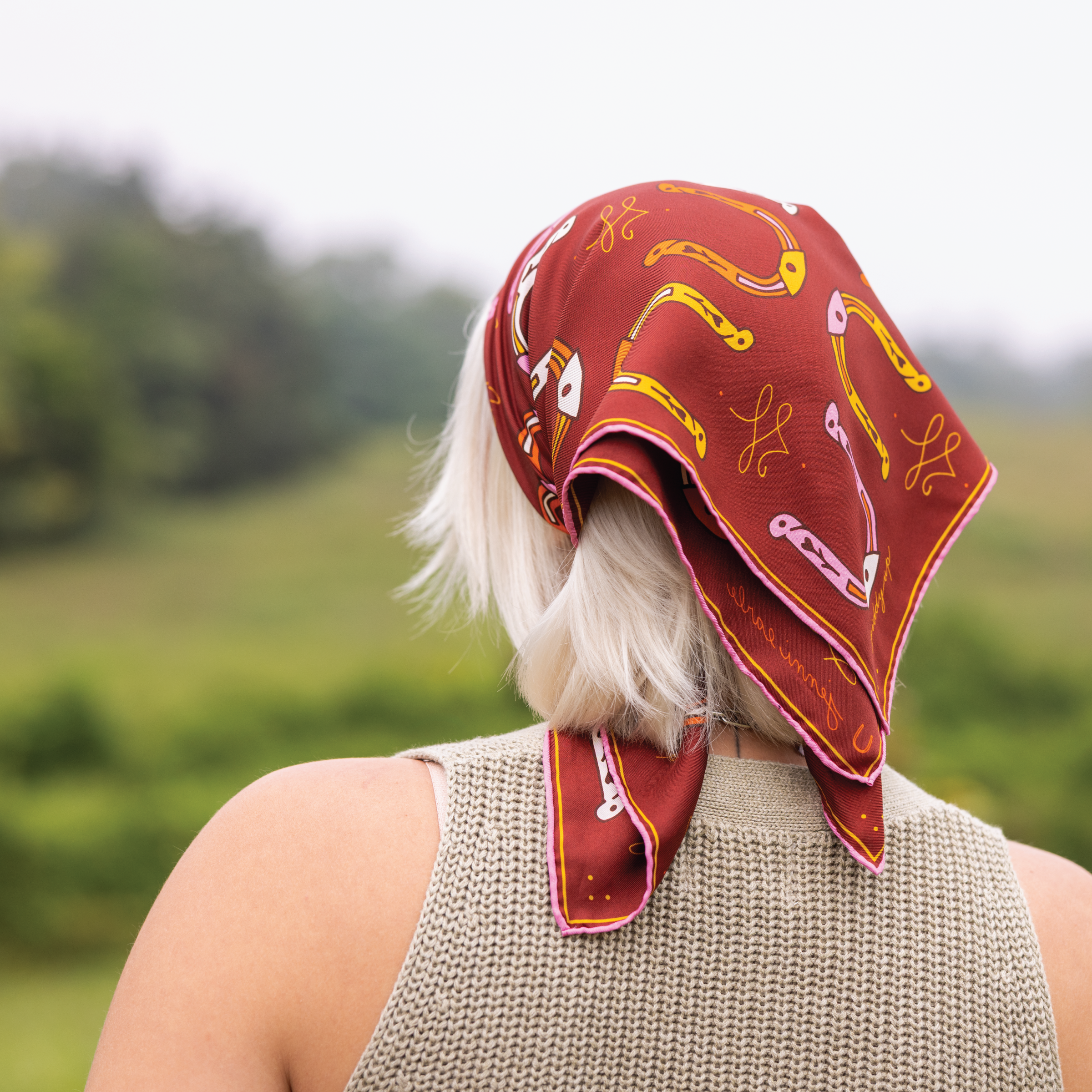 Person wearing a red patterned headscarf with a blurred natural background