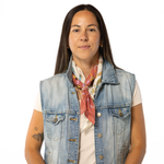 Woman wearing a denim vest and colorful scarf on a white background