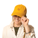 Person wearing a yellow cap with a horseshoe logo on a white background