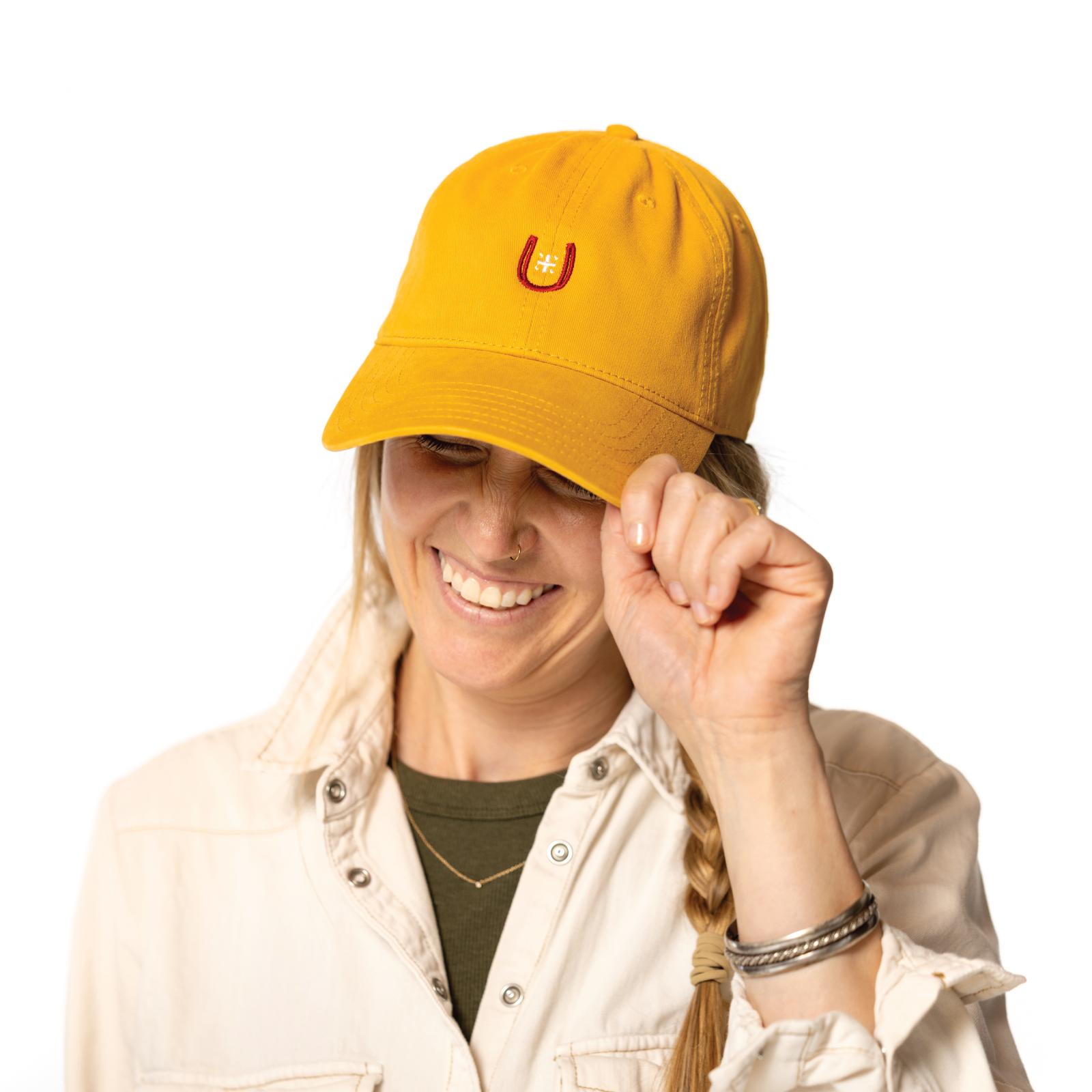 Person wearing a yellow cap with a horseshoe logo on a white background