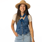 Woman wearing a denim vest, beige hat, and blue scarf on a white background