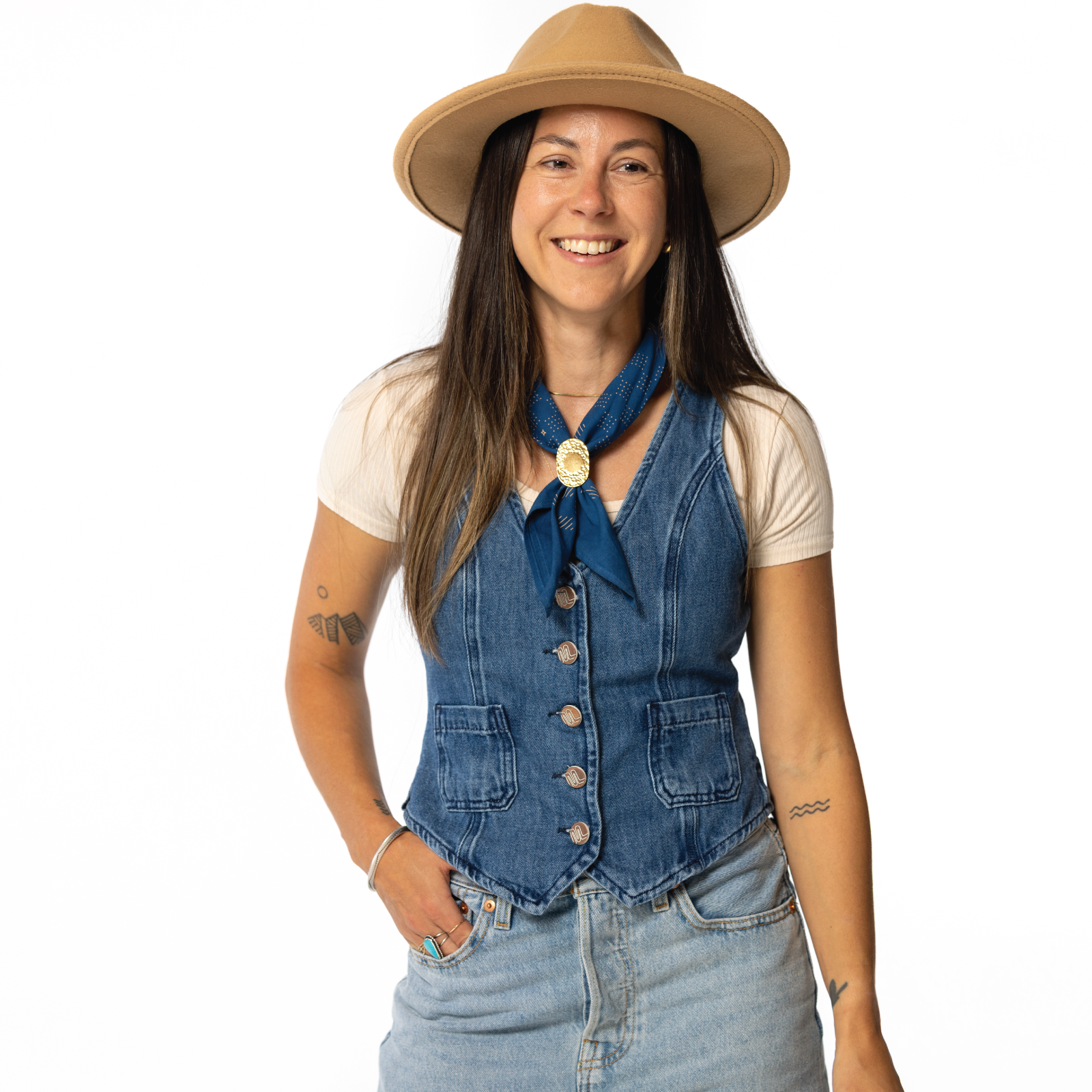 Woman wearing a denim vest, beige hat, and blue scarf on a white background