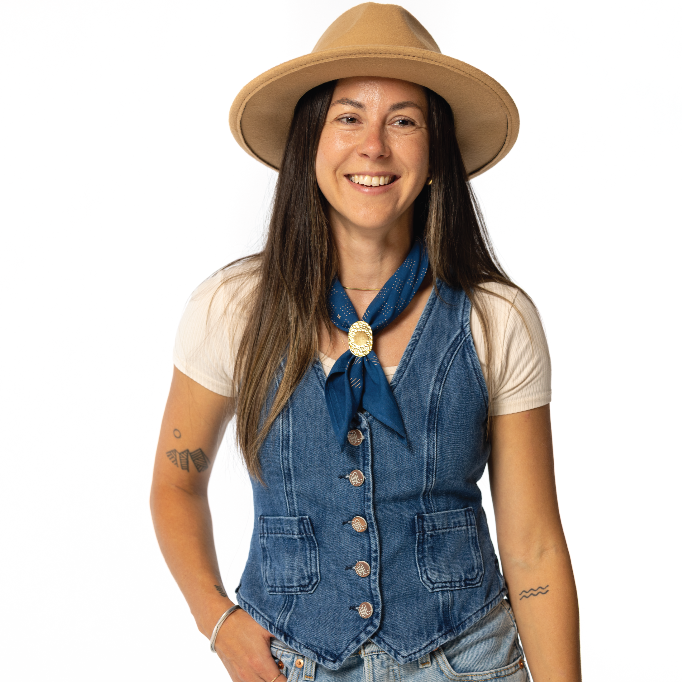 Woman wearing a denim vest, beige hat, and blue scarf on a white background