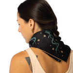 Woman wearing a black scarf with green snake designs on a white background