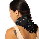 Woman wearing a black scarf with green snake designs on a white background