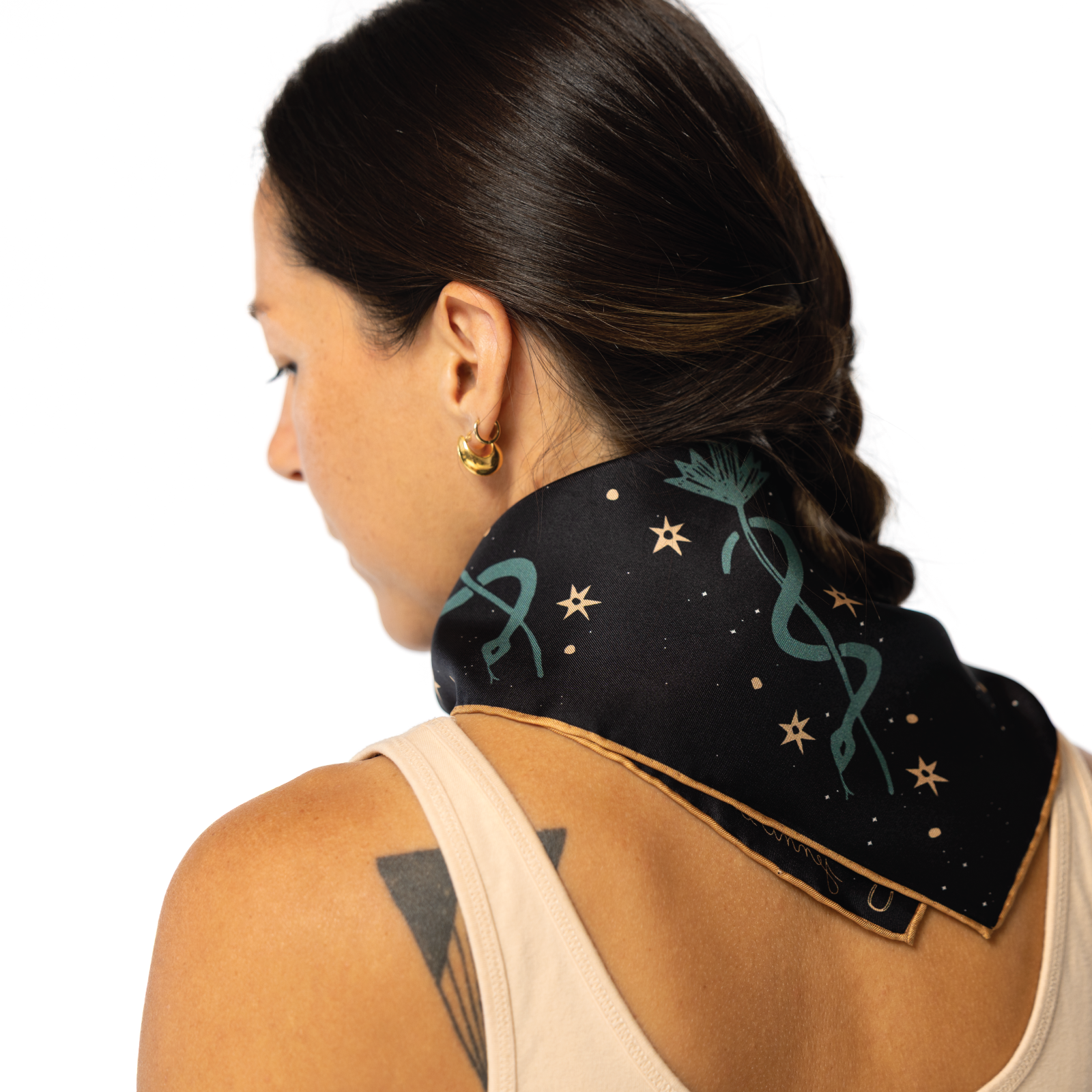 Woman wearing a black scarf with green snake designs on a white background