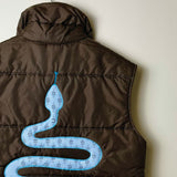 A brown puffer vest shown from the back, featuring a large light blue snake graphic printed across the center.