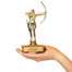 Gold trophy with archer design held by a hand on a white background