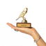 Gold bird trophy with 'YOU'RE SO FLY' plaque held in a hand on a white background
