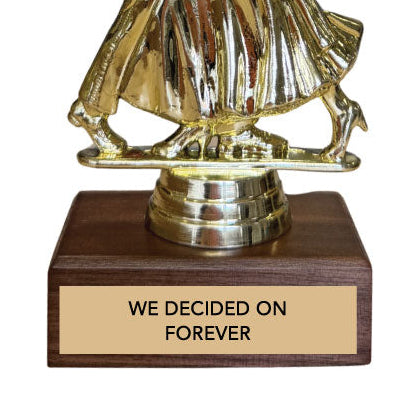 Gold dancing couple trophy with wooden base and engraved text 'we decided on forever' on a white background